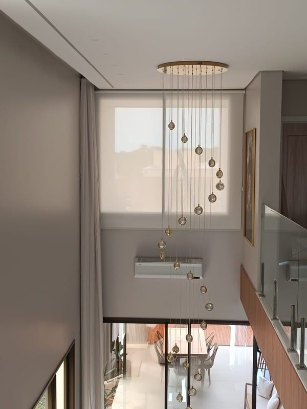 Sala de pé-direito duplo com cortina rolô e cortina de tecido, instaladas pela Cortinas Nordeste